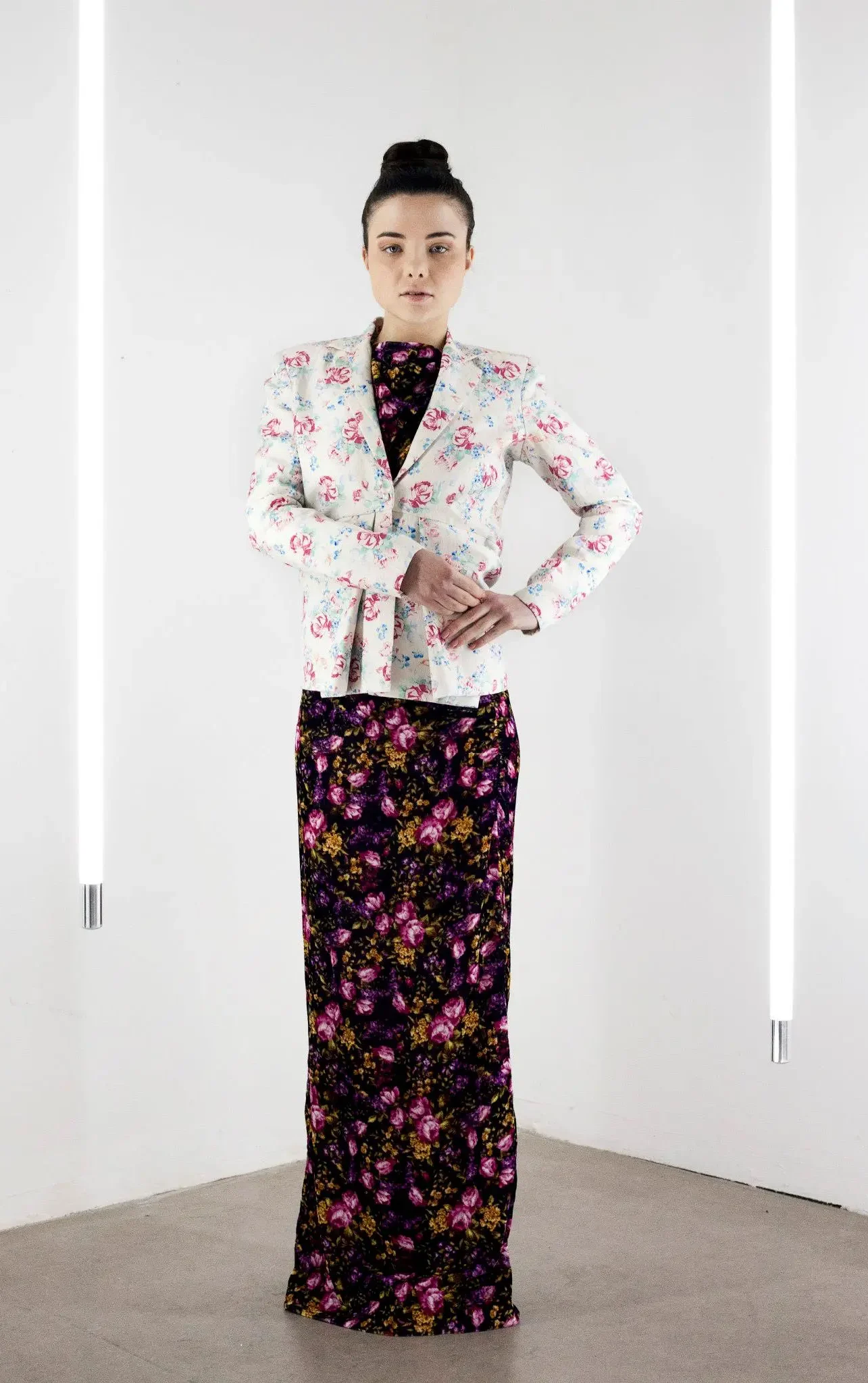 Model wearing a pleated linen jacket layered over a long floral velvet dress, inspired by 1960s Parisian textile designs by Abraham.